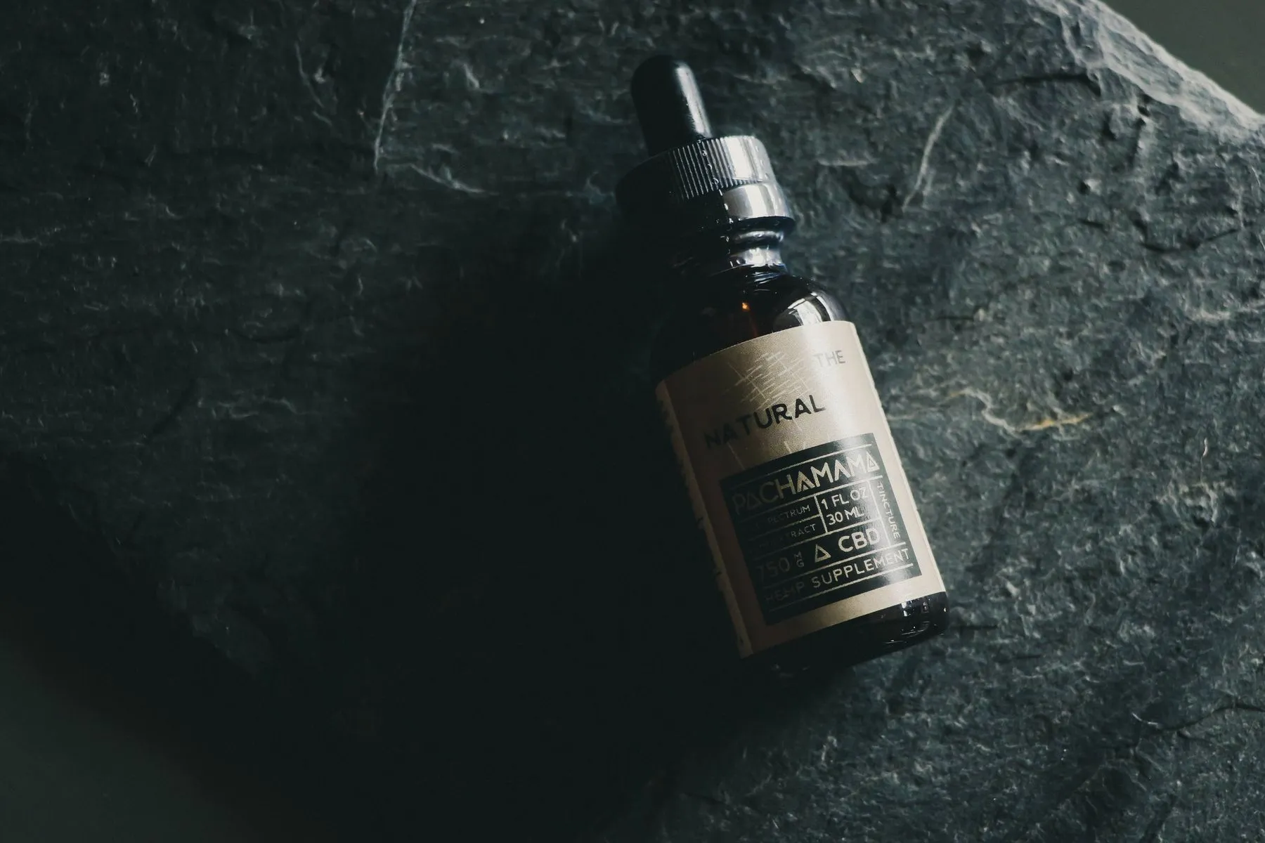A dropper bottle of hemp tincture beside gummies